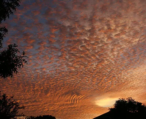 The blue sky, yellow Cirrus clouds and orange Altocumulus clouds result from both Rayleigh and Mie scattering.