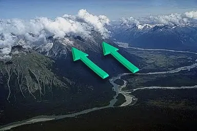 Clouds forming over mountain tops due to wind moving upslope and converging.